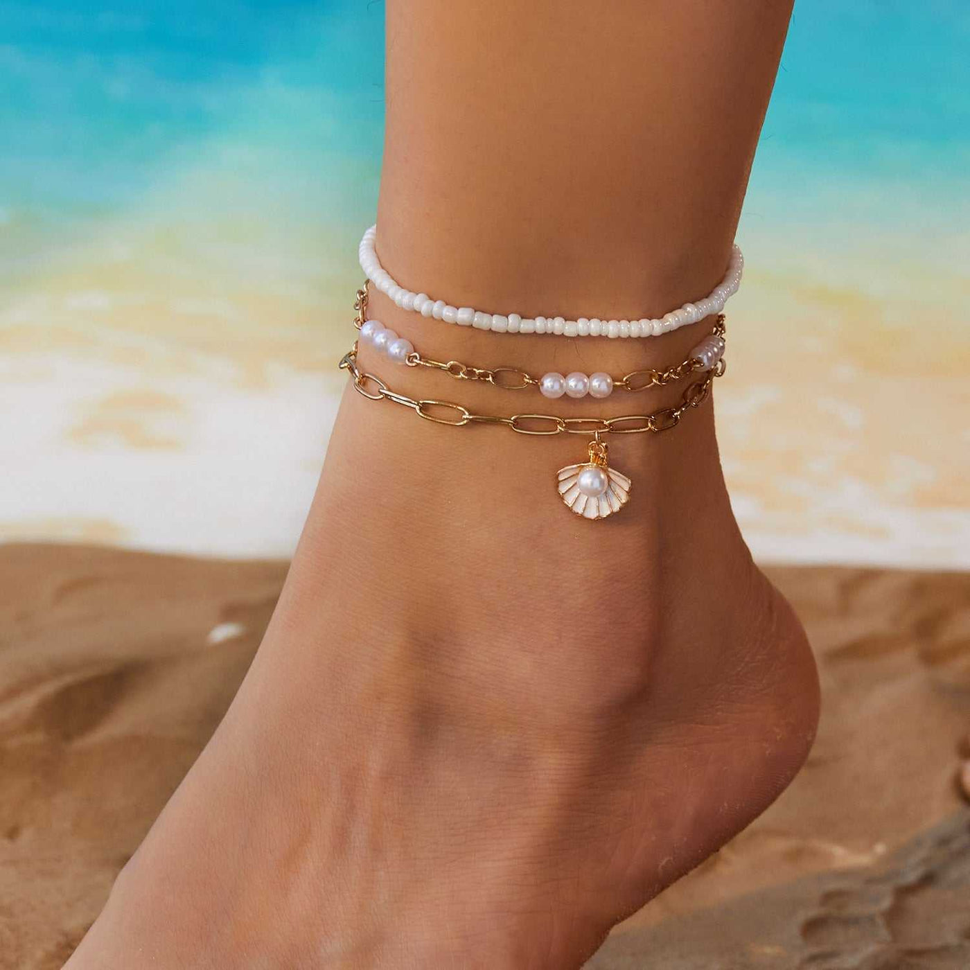 Starfish conch shell pearl multi-layer anklet on ankle with beach background