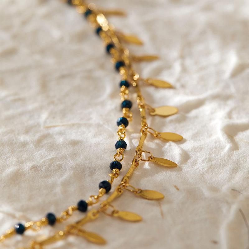 Beach layered retro copper plating 18K real gold anklet with black beads and gold charms on textured fabric background