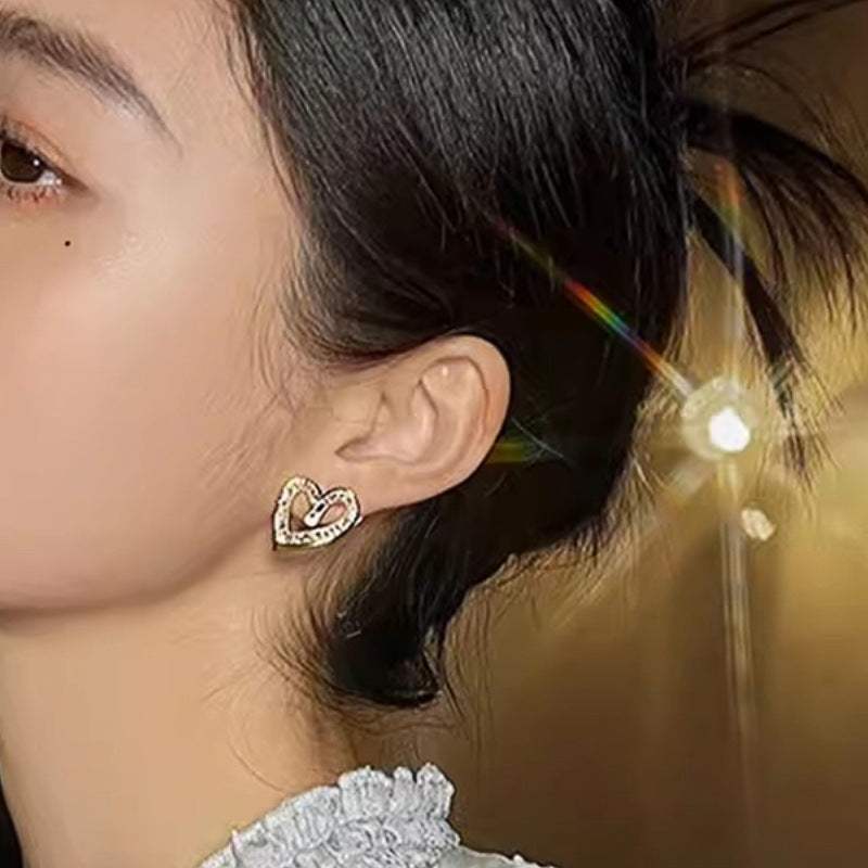 Elegant yellow gold hollowed heart shape ear studs with inlaid zircon worn by woman